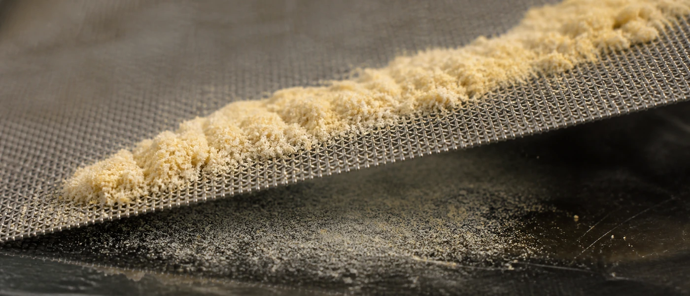 Kief CBD tamisé à la main au-dessus d’un tamis fin dans un atelier